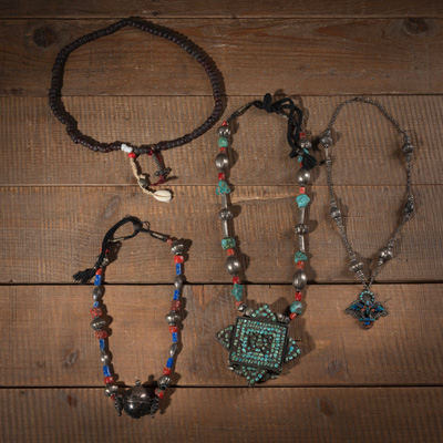 <b>Zwei Ketten mit Amulett-Behältern, Gebetskette mit Fruchtkernen und Kette aus Silber mit Garuda-Anhänger.</b>
