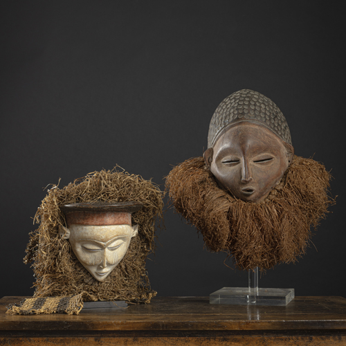 <b>Zwei Masken aus Holz mit Bastbehang, eine mit Kalkfassung</b>