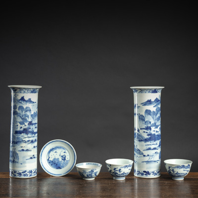<b>Zwei zylindrische Vasen, eine Untertasse und drei Schalen aus Porzellan mit unterglasurblauem Landschaftsdekor</b>