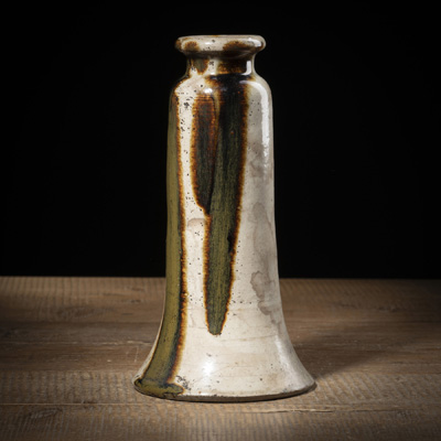 <b>Trompetenförmige Vase aus Steinzeug partiell mit grünlichbraunem Glasurverlauf auf beigem Grund</b>
