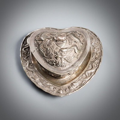 <b>A HEART-SHAPED LIDDED SILVER BOX WITH DRAGONS AND WATER BUFFALO IN RELIEF WITH SAUCER</b>