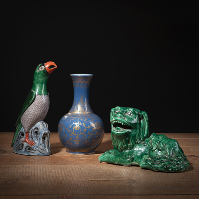 <b>Kleine puderblau glasierte Flaschenvase mit Drachendekor in Gold und zwei grün glasierte Porzellan-Skulpturen von Papagei auf Felsen und liegendem Löwen</b>