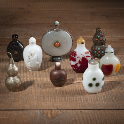 <b>Gruppe von neun Snuffbottles aus Porzellan, zisha-Keramik, Glas,Burgauté-Lack, Metall mit Jade- und Steinbesatz</b>