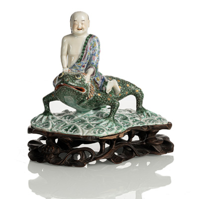 <b>Figur des Liu Hai aus Porzellan mit polychromem Dekor, auf seiner Kröte reitend, Holzstand</b>