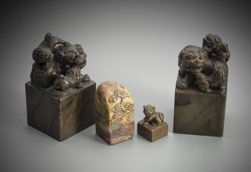 <b>A GROUP OF FOUR SEALS:  TWO SOAPSTONE LION SEALS WITH ENGRAVED SEAL SURFACE, A BRONZE LION SEAL AND A SOAPSTONE SEAL</b>
