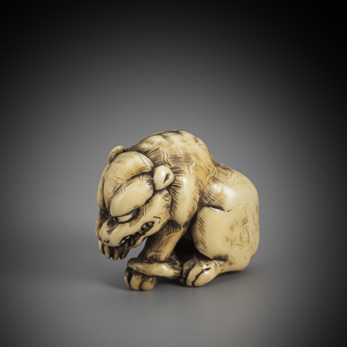 <b>An ivory netsuke of a sitting tiger, licking its right paw</b>