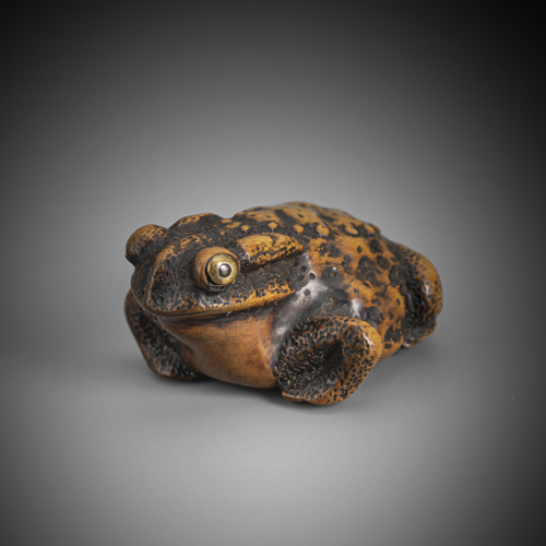 <b>A netsuke of a sitting toad in medium brown boxwood with beautiful age patina and inlaid eyes in horn</b>