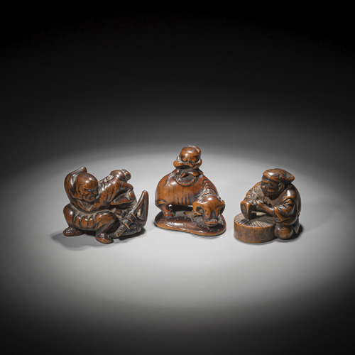 <b>A netsuke of a boy playing the flute on an ox, a netsuke of a seated man with an axe and two wrestling warriors, all carved  in medium brown wood</b>