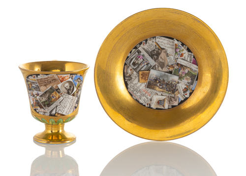 <b>Tasse und Untertasse mit Postkarten- und Zeitungsmotiven in Trompe d'Oeil Manier</b>