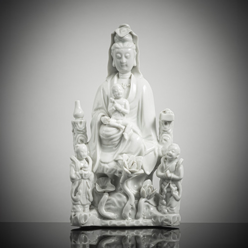 <b>A 'blanc de chine' figure of Guanyin with boys seated on a rock with lotus</b>