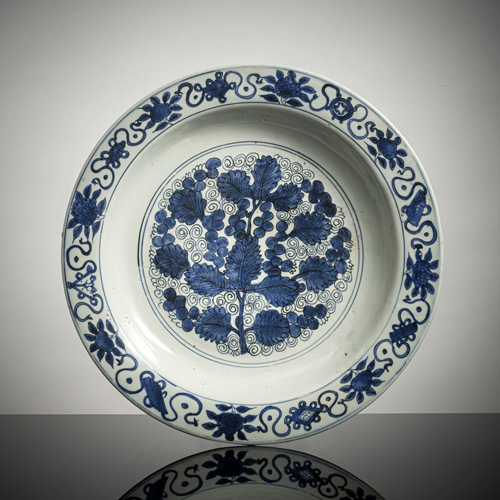 <b>A large blue and white charger with grape and vine leaf decoration and emblems</b>