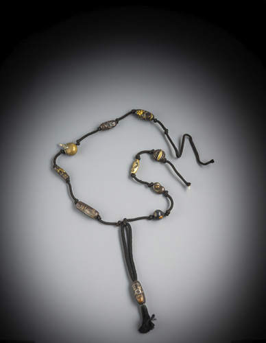<b>A group of 11 metal ojime, partly in iron or decorated with silver, tied in a cord</b>