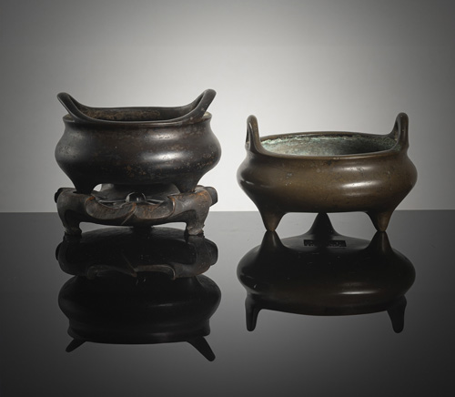 <b>Two bronze tripod incense burners, one with a wooden stand</b>