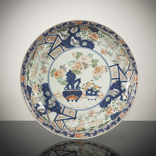 <b>A deep 'imari' porcelain plate with flared lip and fine decoration of peonies and persimmons in cachepots with stones</b>