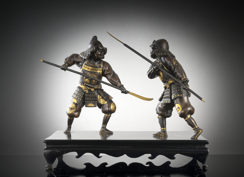 <b>Figurengruppe in mehrfarbigem Metall mit  zwei mit Lanzen kämpfenden Samurai auf Holzstand</b>