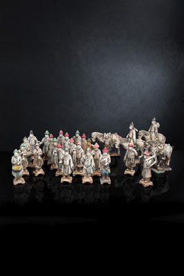 <b>Gruppe von 26 teils glasierten und kalt bemalten Tonfiguren einer Prozession mit Reiterfiguren und Höflingen</b>
