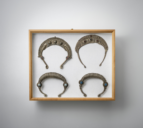 <b>Gruppe von Halsschmuck, Gürtel, Betelschneider und Anhänger, teils in Silber gearbeitet, in zwei Glaskästen montiert</b> <b>Gruppe von Halsschmuck, Gürtel, Betelschneider und Anhänger, teils in Silber gearbeitet, in zwei Glaskästen montiert</b>