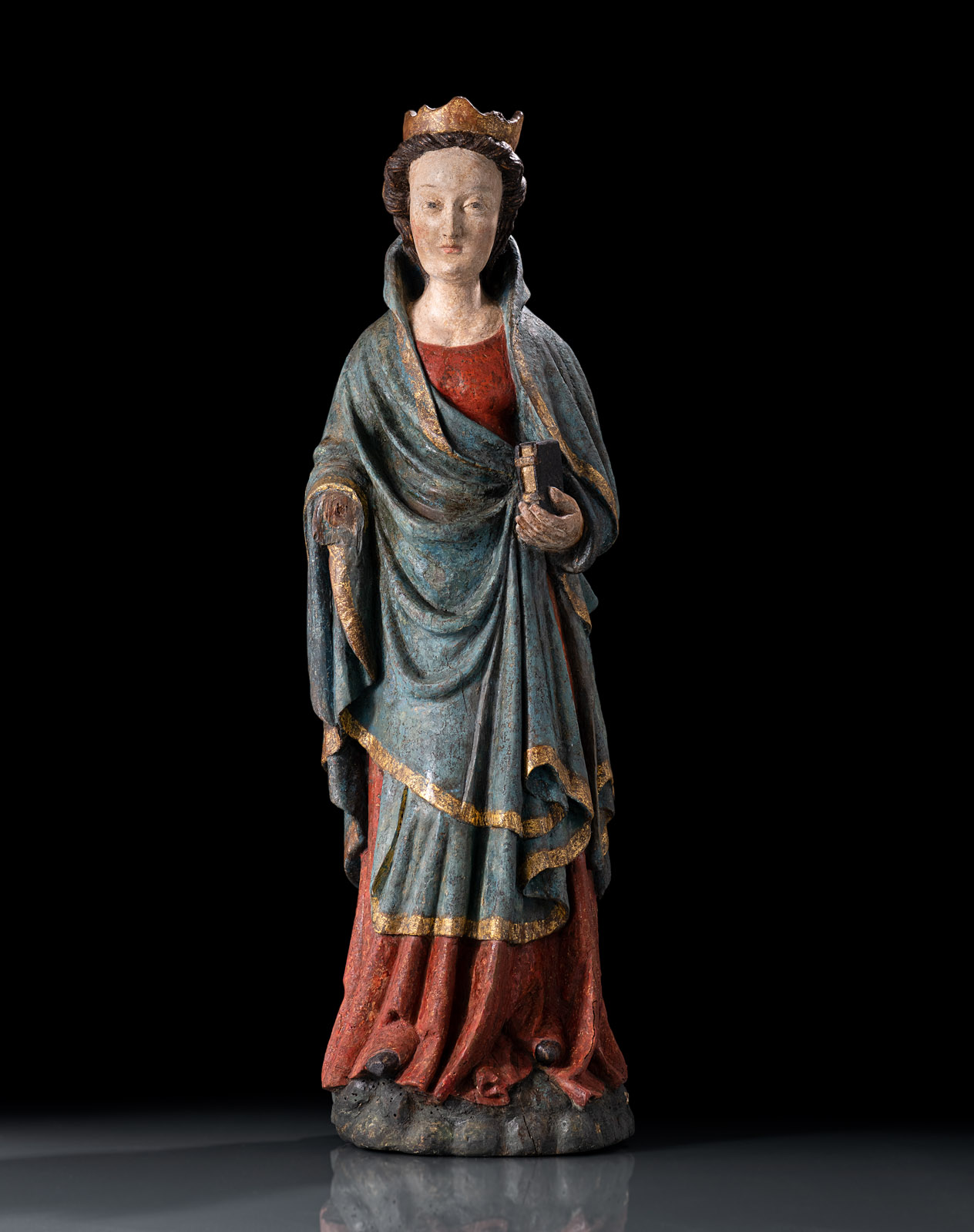 Stehende Figur mit Krone, ein Buch in ihrer linken Hand haltend. Rotes Untergewand und blau-goldener Mantel mit expressivem Faltenwurf. Nussbaum, rückseitig leicht geflacht, weitgehend originale Fassung, großflächig übergangen. Leichte Altersschäden, l. rest.