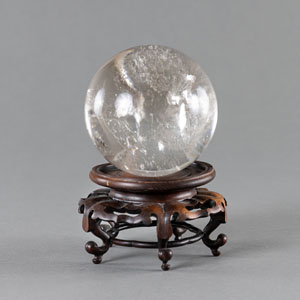 <b>A CRYSTAL SPHERE ON A WOOD STAND</b>