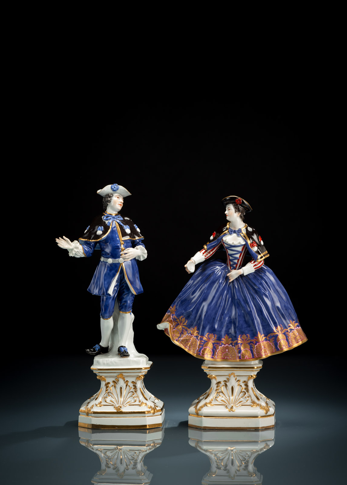 A lady and a gentleman on foliage tooled bases, with pilgrim mussels on their coats, she holds another pilgrim mussle in her hand. Models by Johann J. Kaendler in 1744. Blue sword marks, model no. 680 and 680x. Minor restoration.