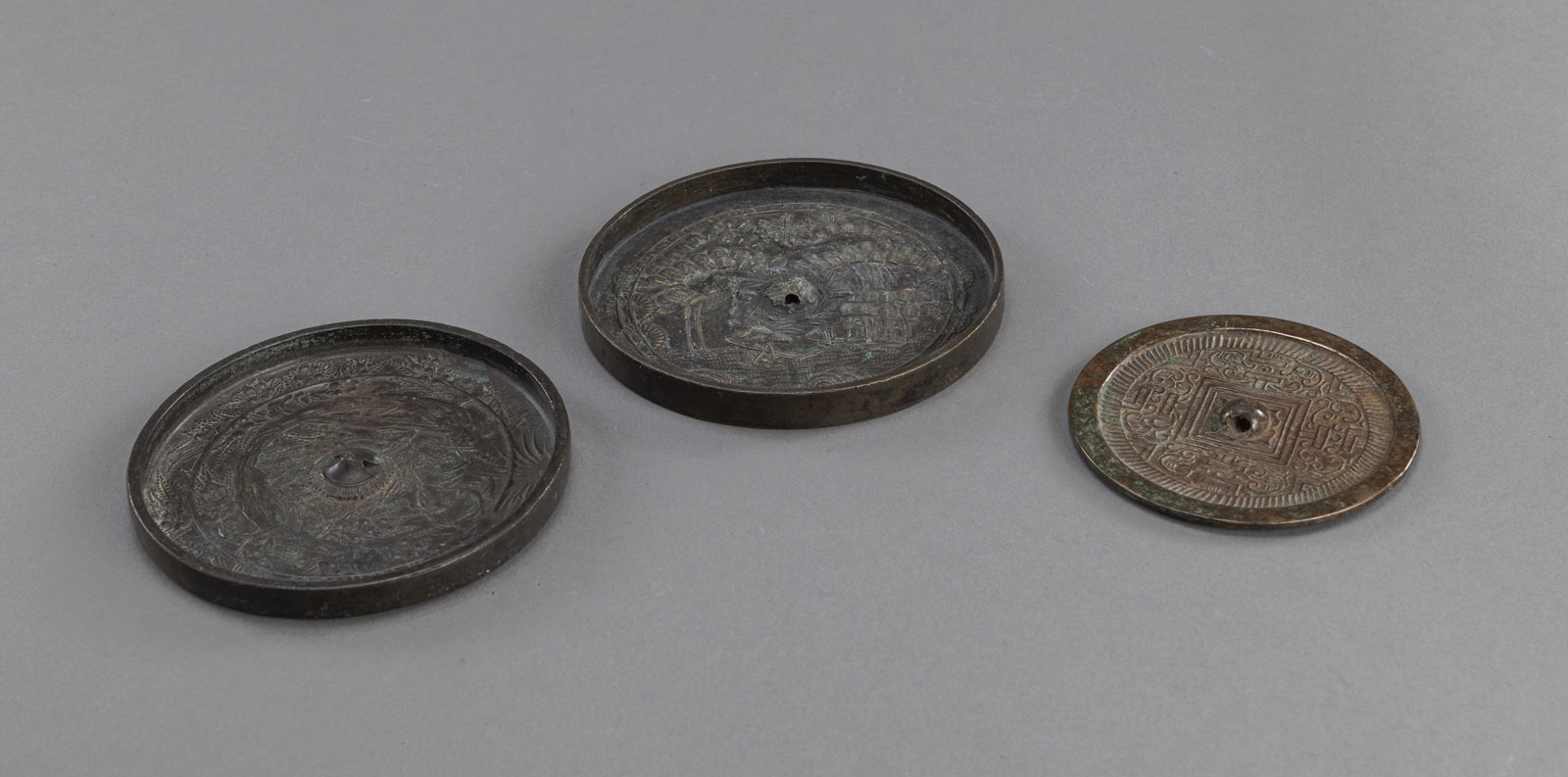 <b>Drei runde Spiegel aus Bronze mit reliefiertem Dekor</b>